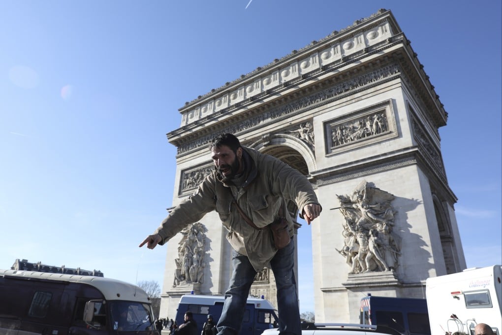 A protester stands on a vehicle as the convoy drives past the Arc de Triomphe. Photo: AP