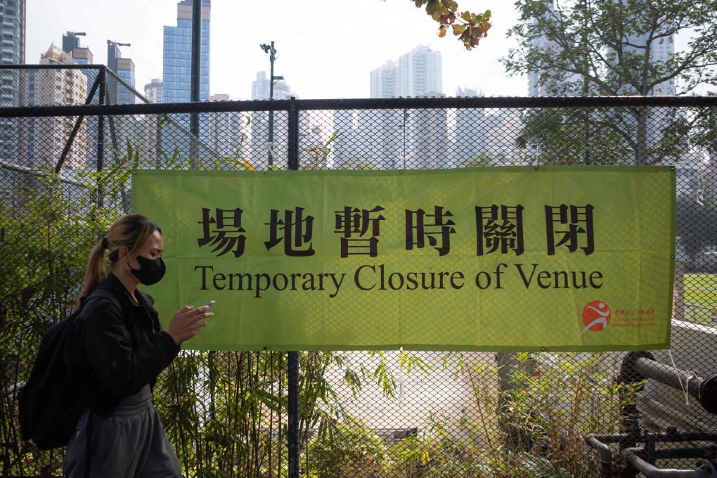 A woman walks past a banner announcing the closure of a venue in Causeway Bay on January 8. Hong Kong’s wholesale closure of facilities is hurting its economy. Photo: AFP