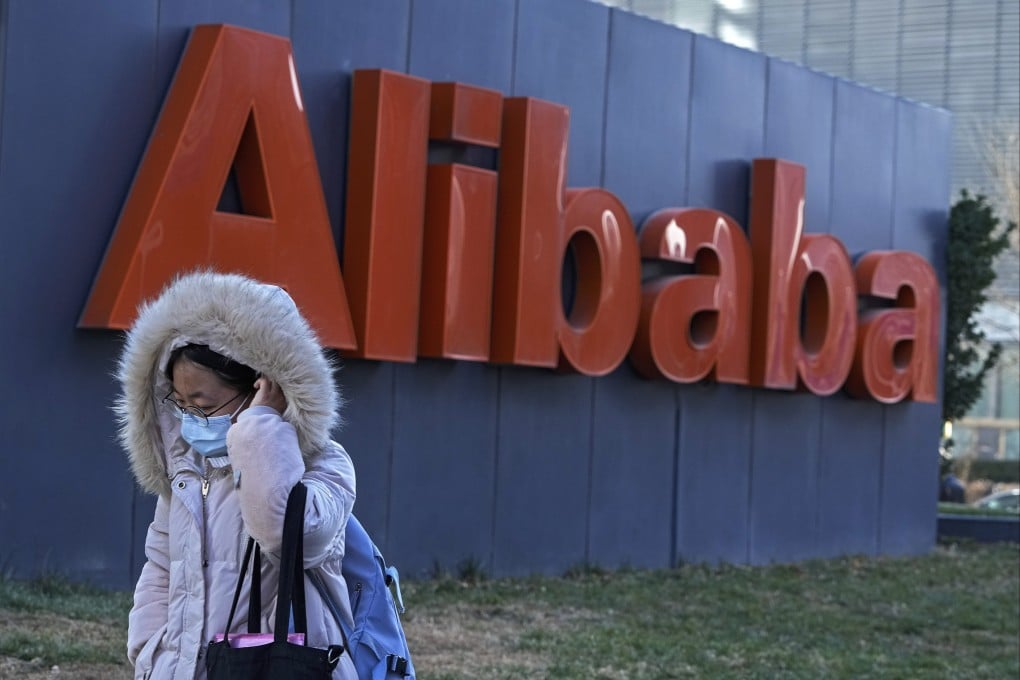 A woman wearing a face mask walks by the offices of Chinese e-commerce firm Alibaba in Beijing. Photo: AP Photo