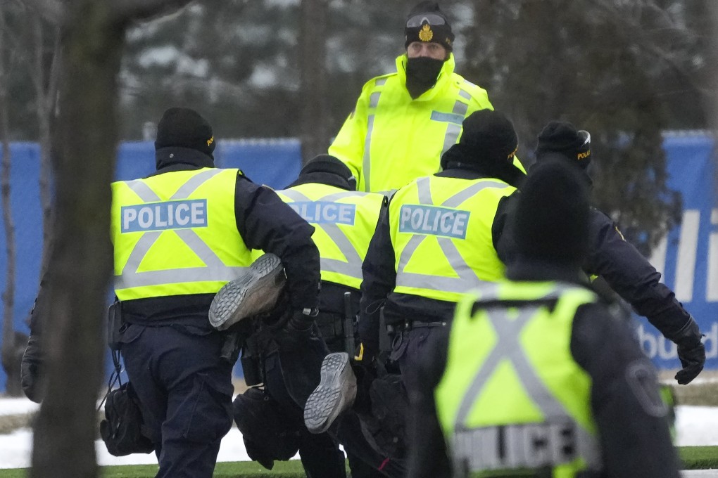 Police arrest a person as they walk the line to remove all truckers and supporters from the Ambassador Bridge, linking Detroit and Windsor. Photo: AP