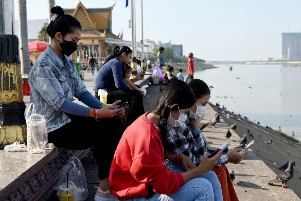 People use smartphones along a riverside in Phnom Penh. Photo: AFP