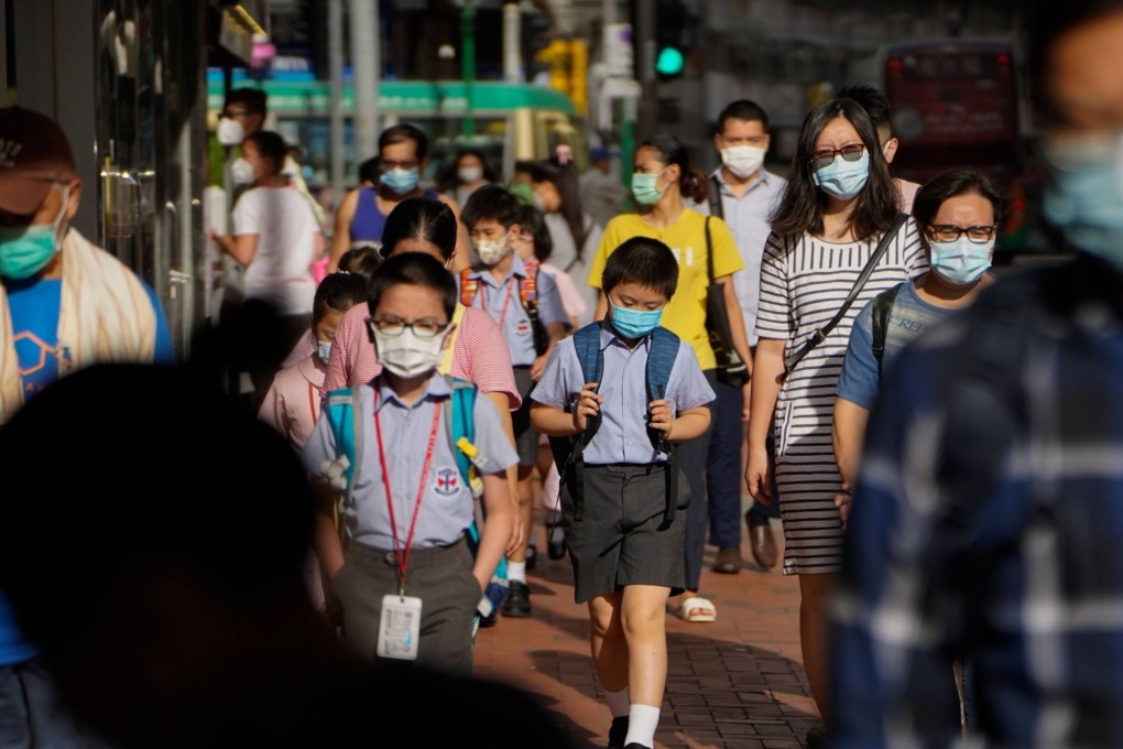 Pedestrians and schoolchildren wearing protective masks walk along a sidewalk in Hong Kong. File photo: Bloomberg