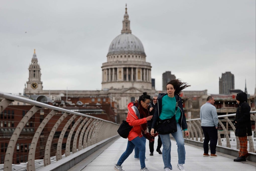 Pedestrians struggle as they cross The Millennium Bridge, London, during Storm Eunice. Photo: AFP