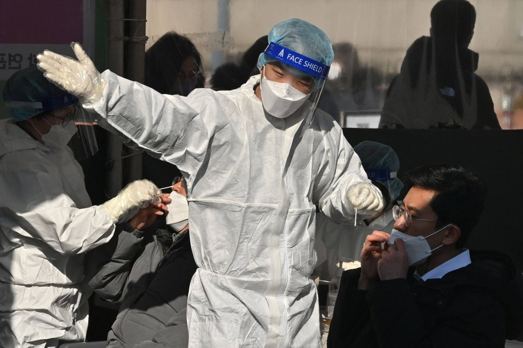 A medical worker in protective gear directs a man after taking a nasal swab at a Covid-19 testing centre in Seoul. Photo: AFP