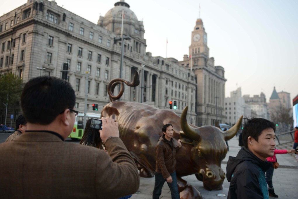 Vistors taking photo of a replica of the famous Wall Street bull on the Bund in Shanghai. Photo: AFP