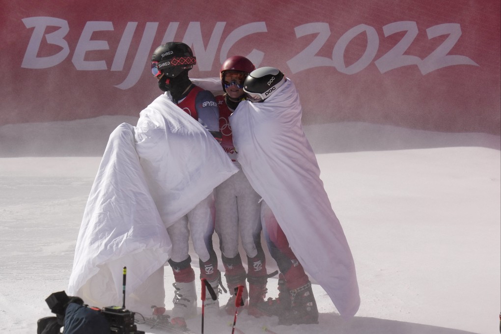 US skier Mikaela Shiffrin (centre) and her teammates stay warm with blankets after losing their semi-final in the mixed team parallel skiing event on Sunday. Photo: AP
