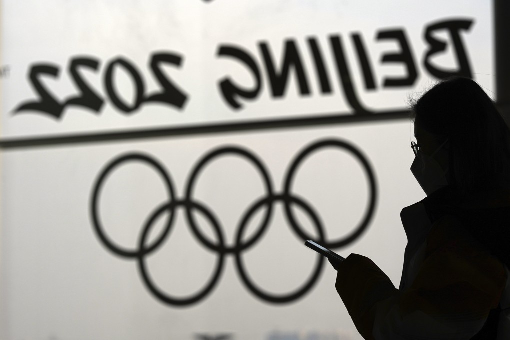 FILE - A woman looks at her phone as she passes an Olympic logo inside the main media centre for the 2022 Winter Olympics. Photo: AP