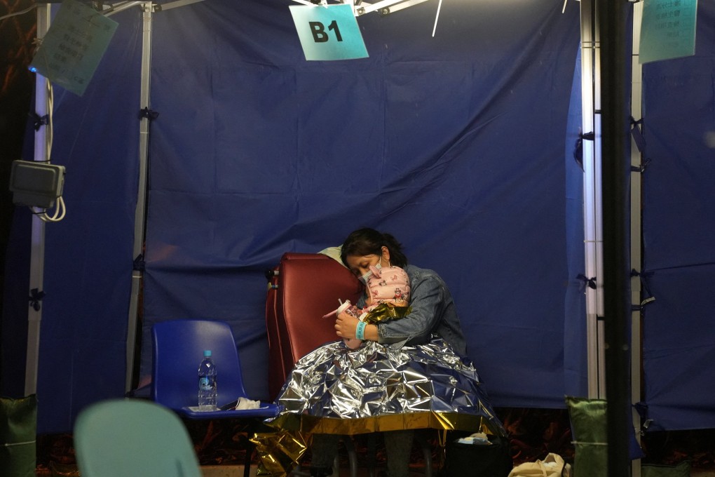 A woman holds a child while sitting at a makeshift treatment area outside a hospital on February 17. A successful Covid-19 policy relies on two crucial factors: a high vaccination rate and a health care system that is not overburdened. Photo: Reuters