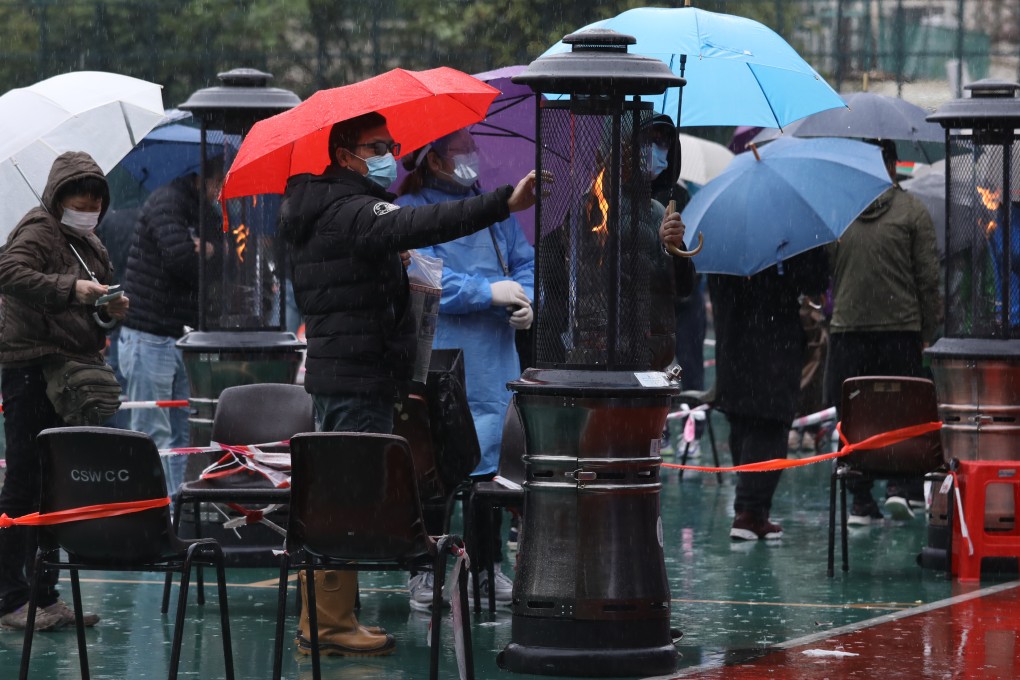 A Hong Kong resident warms himself while waiting to be tested in Sham Shui Po. Photo: Yik Yeung -man