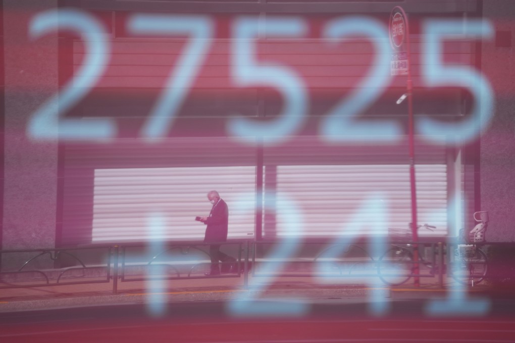 A man is reflected on a monitor showing Japan’s Nikkei 225 index at a securities firm in Tokyo on February 9. Rising inflation and the coming interest rate hikes are of concern to investors everywhere. Photo: AP