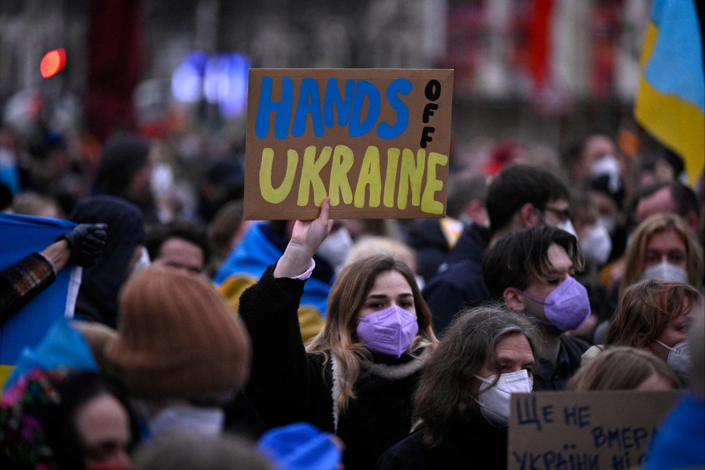 A demonstrator holds a placard reading “Hands off Ukraine” during a rally in front of the Russian embassy in Berlin on Tuesday. Photo: AFP