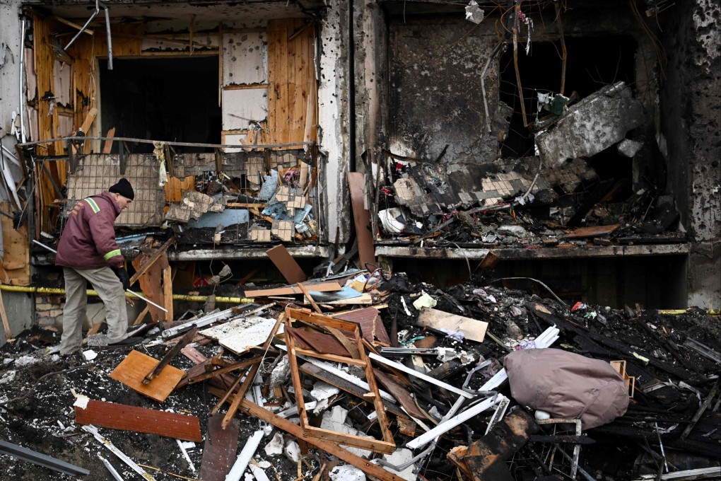 A man clears debris at a damaged residential building in the Ukrainian capital Kyiv, where a military shell allegedly hit, on Friday. Photo: AFP