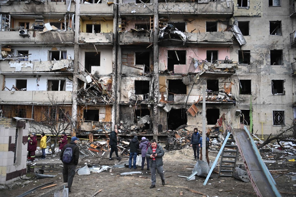 People gather in front of a damaged residential building at Koshytsa Street, a suburb of the Ukrainian capital Kyiv, where a military shell allegedly hit, on February 25, 2022. Photo: AFP