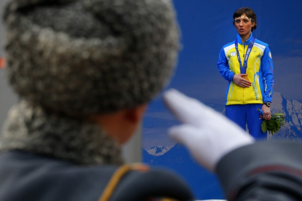 FILE - A Russian honour guard soldier salutes as Ukraine’s Oleksandra Kononova covers her gold medal with her hand after winning the women’s biathlon 12.5km standing event during a medal ceremony at the 2014 Winter Paralympics. Photo: AP
