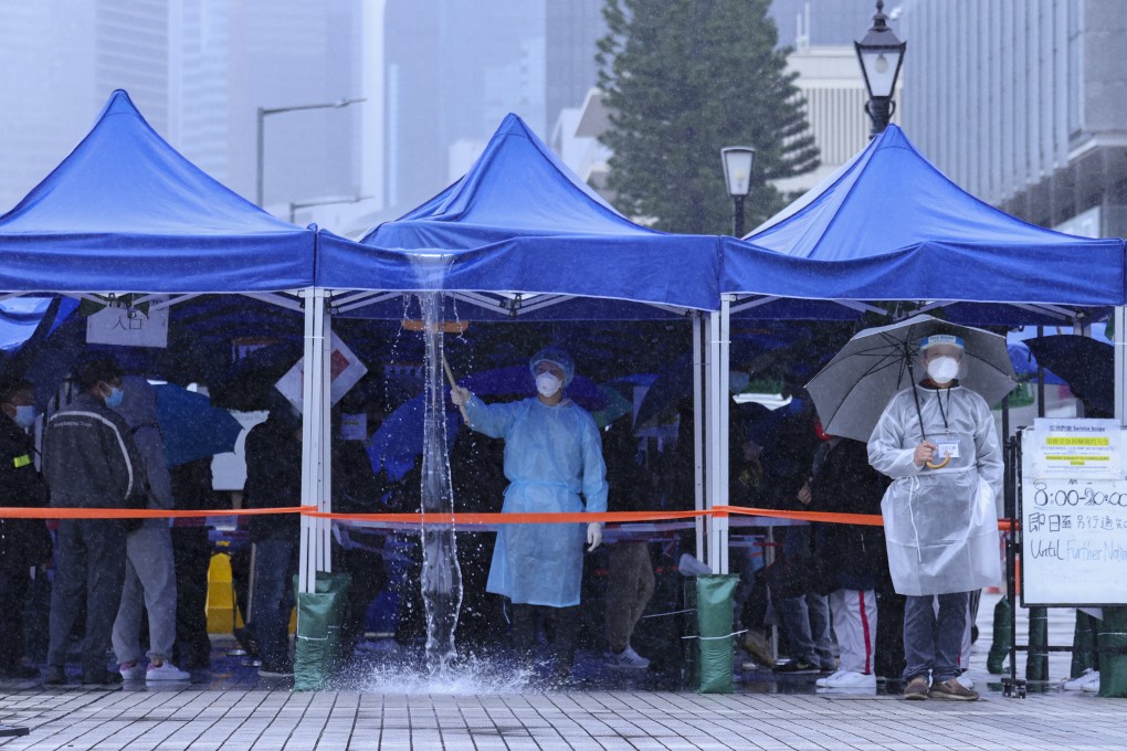 A health worker removes rainwater from a temporary Covid-19 testing tent in Central on February 20. Photo: Nora Tam