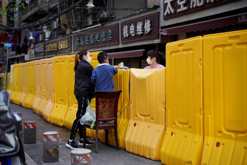 A woman pays for vegetables over barriers set up during Wuhan’s lockdown in 2020. Photo: Reuters