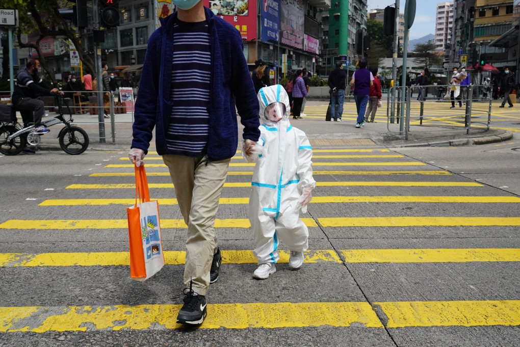 A child wearing a  protective suit walks with an adult in Mong Kok on February 28. Photo: Felix Wong