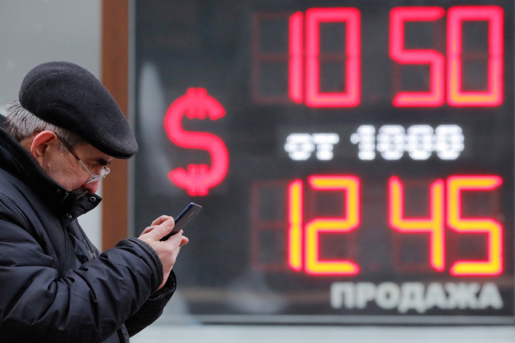 A man stands in front of a board showing the exchange rate of the US dollar against the Russian rouble in St Petersburg, Russia, on February 28. Photo: Reuters