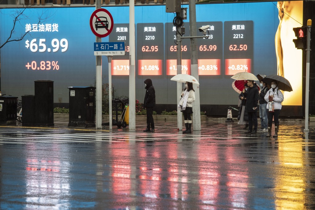 Pedestrians wait to cross a road in front of a public screen displaying market activity in Shanghai in February 2022. Photo: Bloomberg