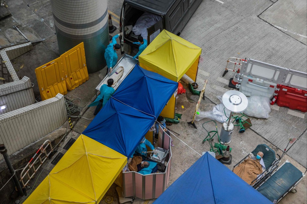 Funeral home staff load a body onto a vehicle near patients being treated at a makeshift area outside Caritas hospital in Hong Kong on March 2. Photo: AFP