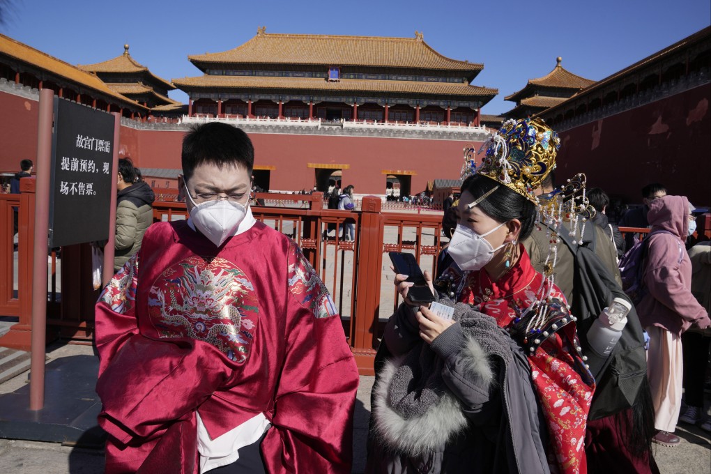 People dressed in period costumes keep their masks on outside the entrance to the Forbidden City in Beijing. Photo: AP