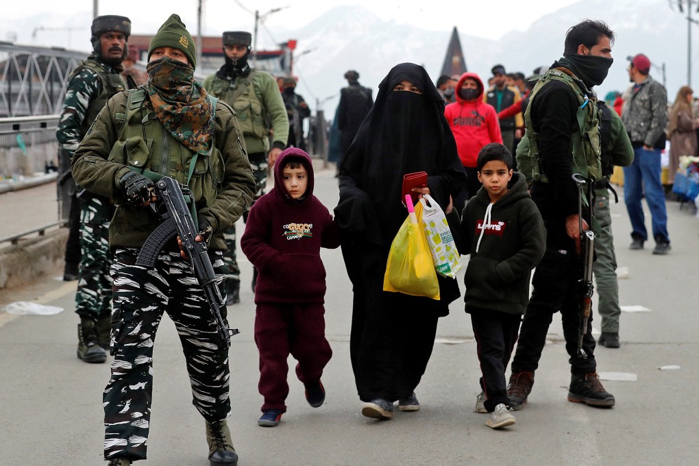 A veiled woman walks with her children past Indian security forces near the site of a grenade explosion in Srinagar, India on March 6. Photo: Reuters