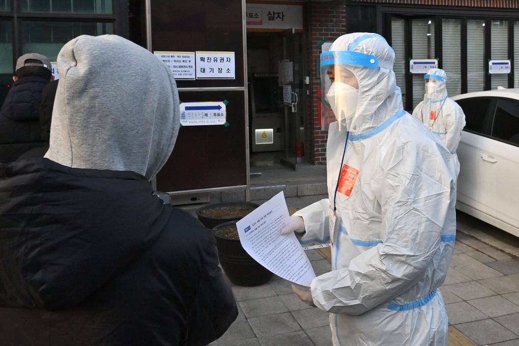 South Korean election officials wearing protective gear guide voters infected with the Covid-19 coronavirus at a polling station for the March 9 presidential election. Photo: AFP