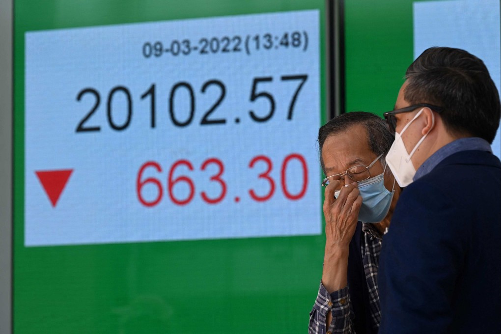 Two men chat in front of an electronic sign showing the Hang Seng index in Hong Kong on March 9, 2022. Photo: AFP