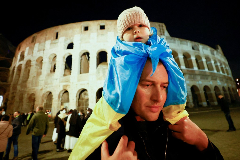 A child wrapped in the flag of Ukraine is carried during a candlelight march to call for peace and show solidarity with Ukrainians, outside the Colosseum in Rome, Italy, on February 25. Photo: Reuters