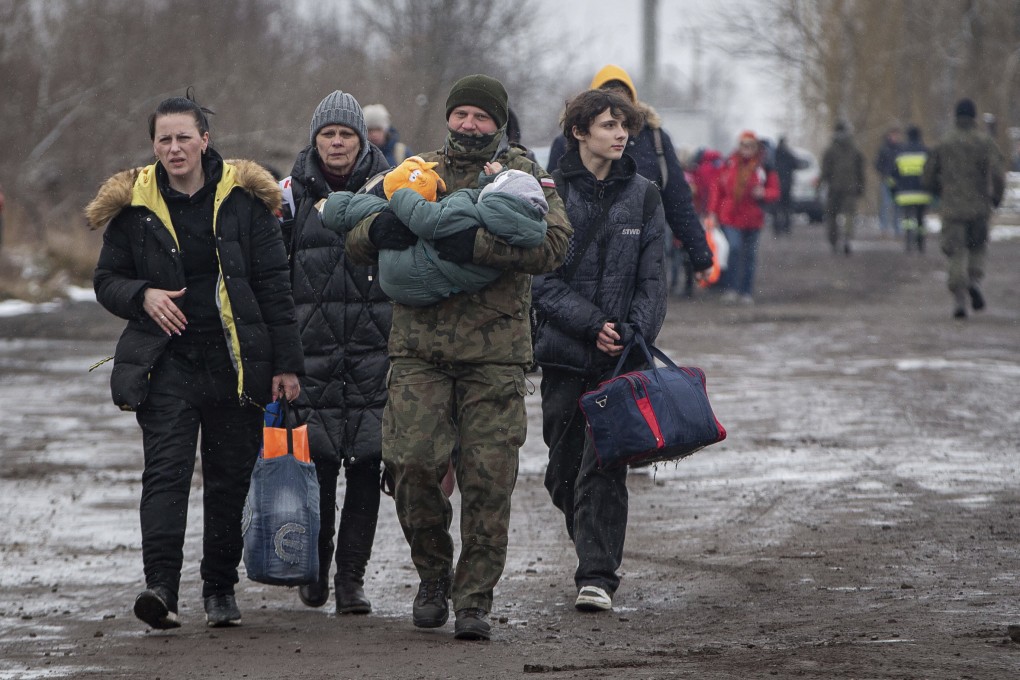 A Polish soldier carries a child as Ukrainians head to Krakow. Photo: AP