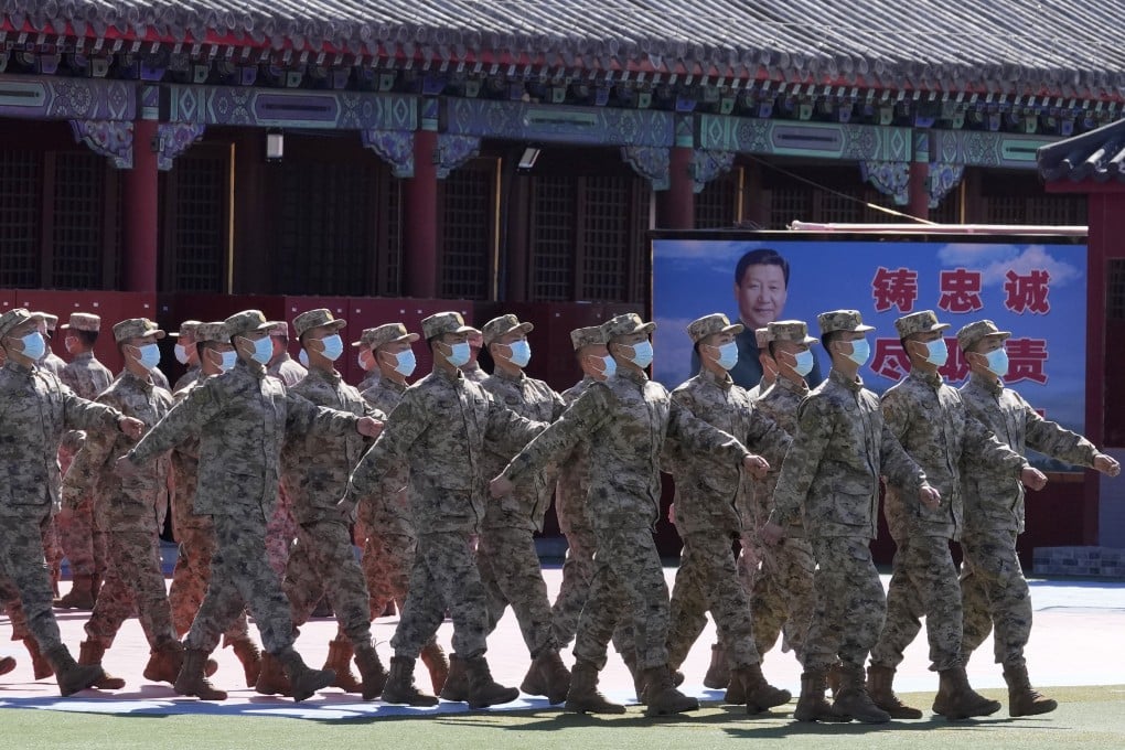 Members of a Chinese military honour guard march past a poster showing President Xi Jinping and slogans calling for loyalty and duty, in Beijing on Saturday. Photo: AP