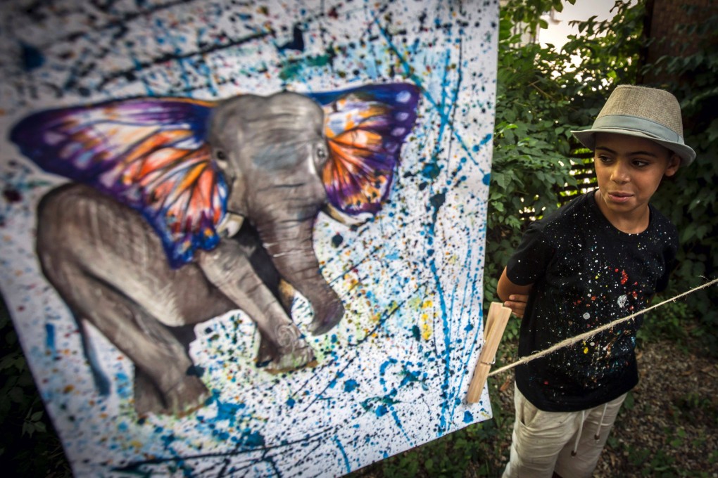 10-year-old Farhad Noory, a refugee from Afghanistan, looks at one of his artworks on show in Belgrade, Serbia, in . Artistic talent is often the only thing desperate refugees can bring when they flee oppression or disaster. Photo: AFP