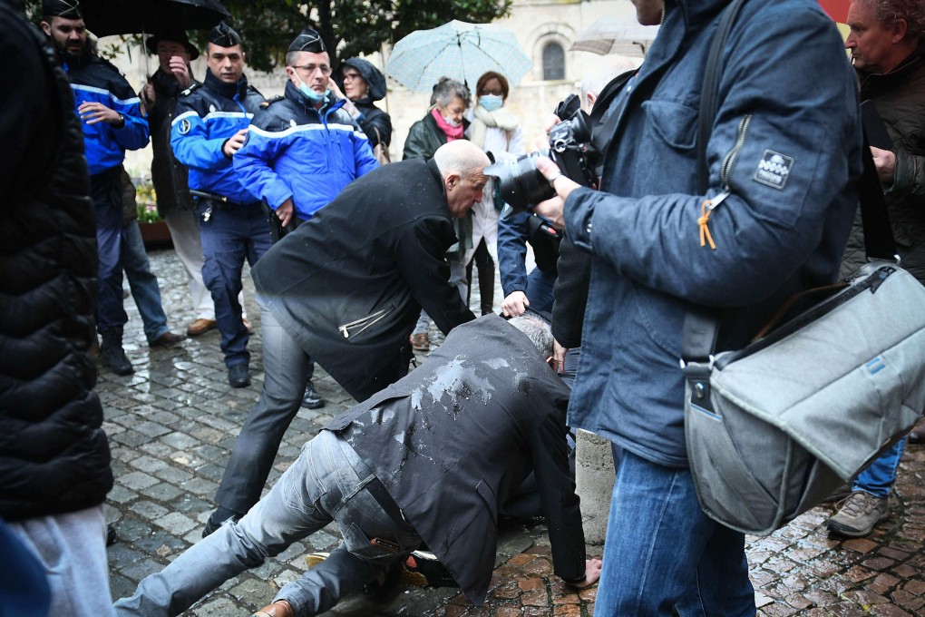 An unidentified man (hidden, on the ground) is arrested after throwing an egg at French presidential candidate Eric Zemmour during a campaign visit in Moissac, southern France, on March 12. Photo: AFP