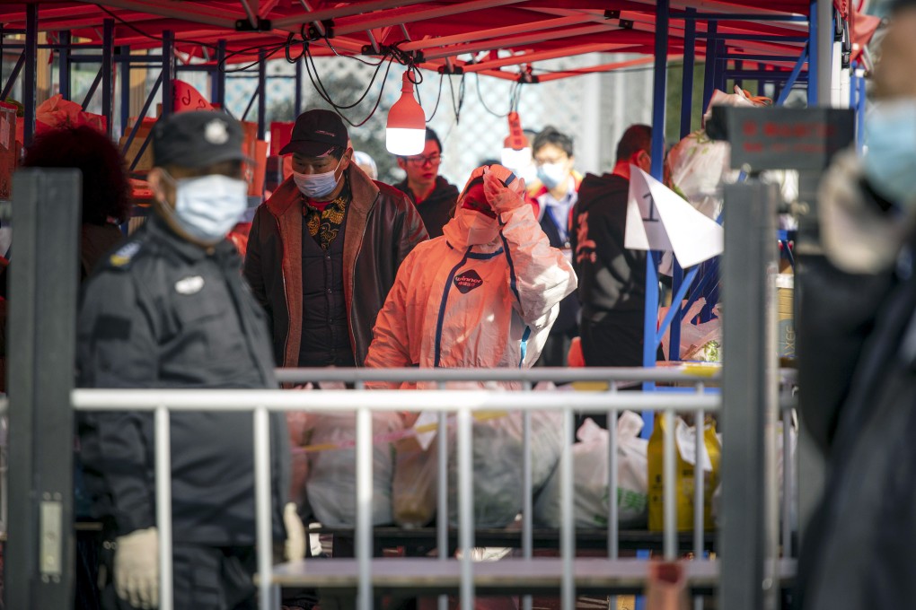 A worker wearing personal protective equipment (PPE) helps transport deliveries of food and other necessities from couriers to residents of neighbourhood placed under lockdown due to Covid-19 in Shanghai, on March 10, 2022. Photo: Bloomberg