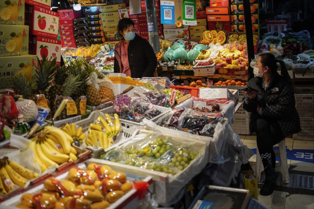 A vendor chats to a customer at a market in Beijing on March 9. According to the National Bureau of Statistics, China’s consumer price index rose 0.9 per cent year on year in February. Photo: EPA-EFE