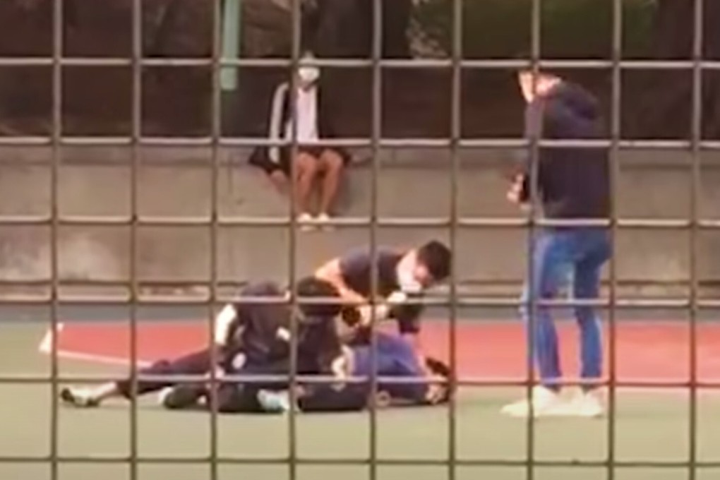 A still from a video posted online shows a 15-year-old boy being subdued by three plain-clothes policemen after being caught with his 13-year-old brother playing basketball without wearing face masks, on March 8. Photo: YouTube