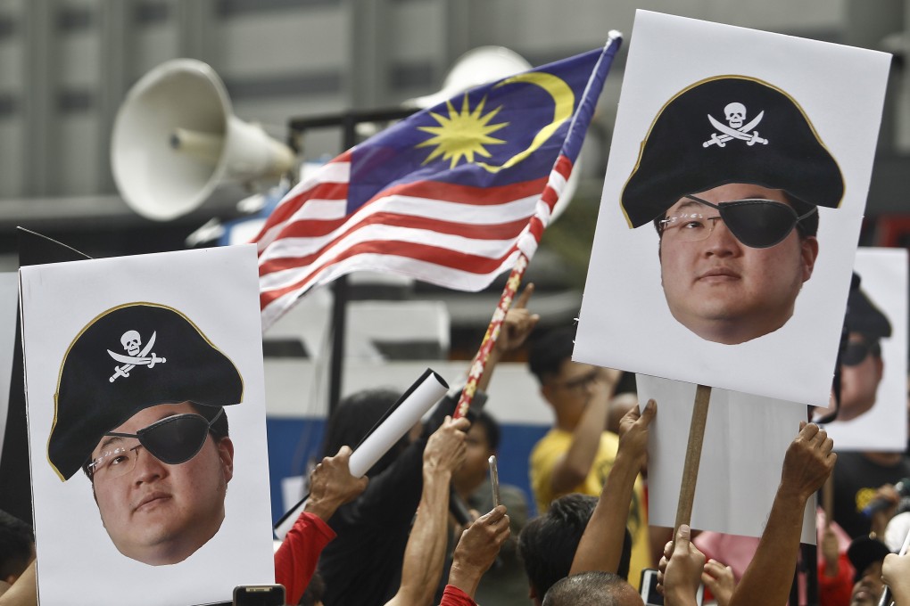 Demonstrators hold portraits of Jho Low illustrated as a pirate during a protest in Kuala Lumpur. File photo: AP