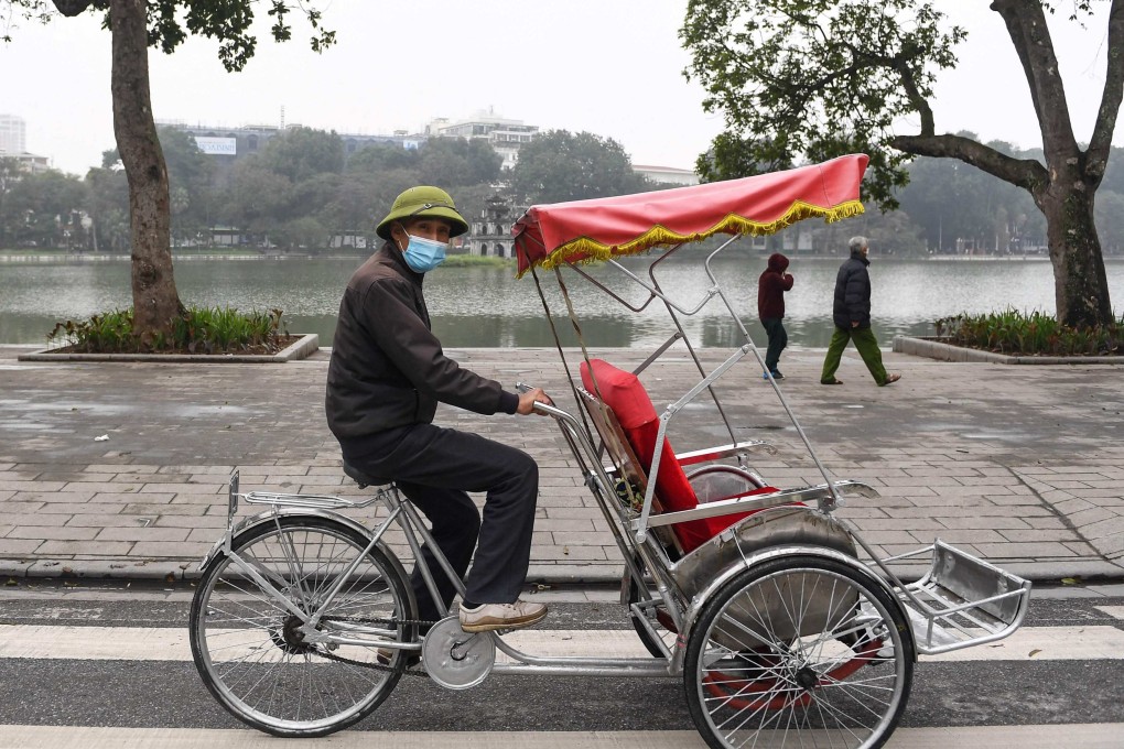 A driver looks for customers along Hoan Kiem Lake in downtown Hanoi. Photo: AFP