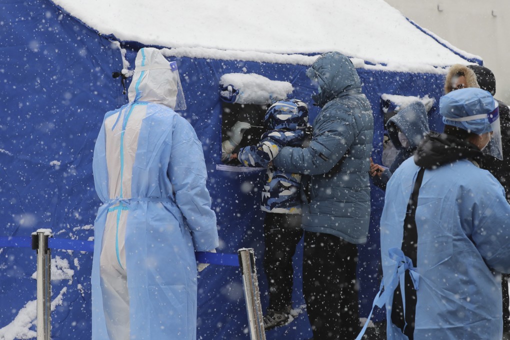 A child is lifted up for a nucleic acid swab as people queue in the snow for Covid-19 tests in Changchun, in northeastern China’s Jilin province. Photo: AP