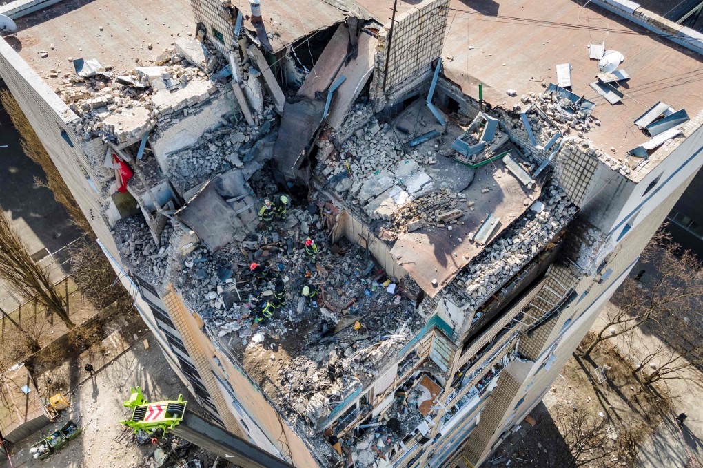 An aerial view shows firemen working in the rubble of a residential building which was hit by the debris from a downed rocket in Kyiv on March 17, 2022. Photo: AFP