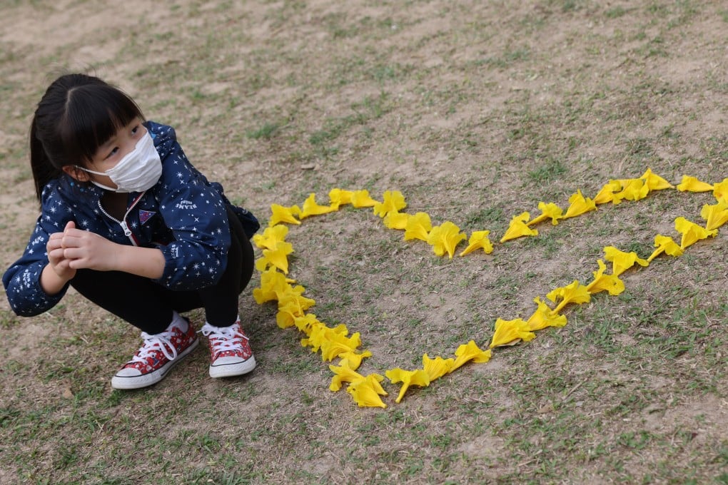 People admire and take pictures of the blossoming yellow Golden Trumpet Tree flowers at Nam Cheong Park in Nam Cheong on March 17. Research suggests people are more likely to engage in healthy behaviours such as wearing masks when they feel empowered to take care of themselves during the pandemic. Photo: Nora Tam