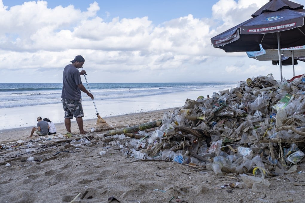 A worker cleans up piles of debris and plastic waste brought in by strong waves at Kuta Beach in Bali, Indonesia, on December 10, 2021. Photo: EPA-EFE