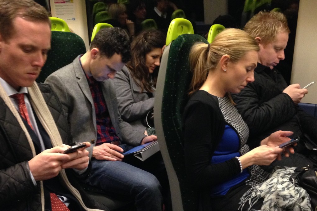 Commuters on a train to London looking at their mobile phones. The internet is addictive by design and that’s not a good thing. Professor Justin Smith argues. Photo: Getty Images