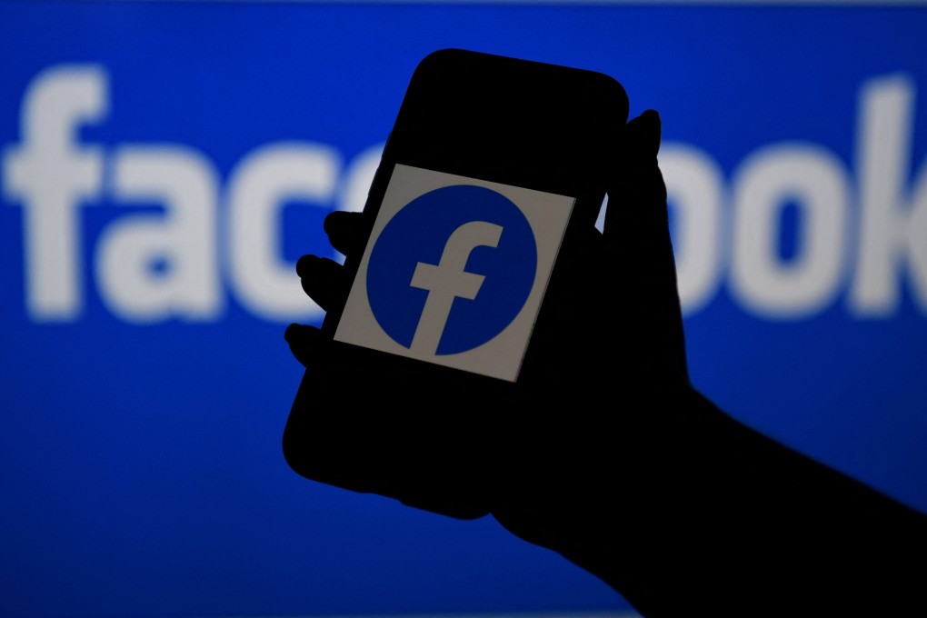 Asmart phone screen displays the logo of Facebook on a Facebook website background. Photo: AFP
