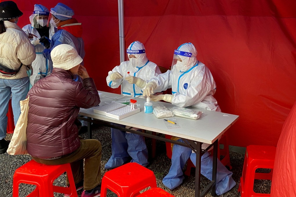 Medical workers in protective suits conduct nucleic acid test for a resident at a makeshift testing site in Shanghai on Sunday. Photo: Reuters