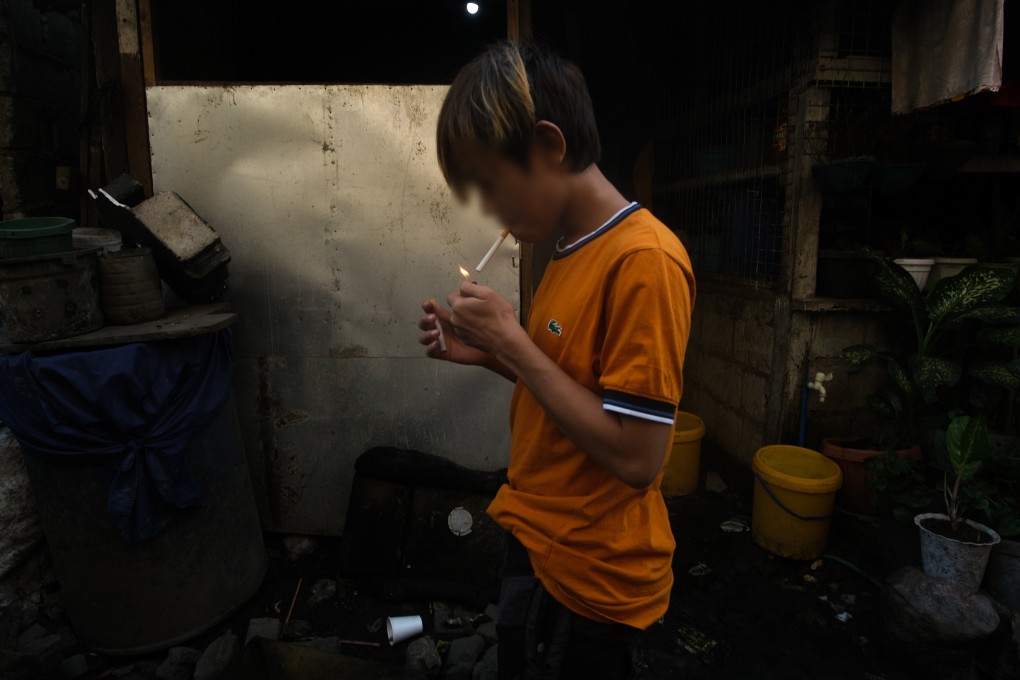 Rofwiel, 14, lights a cigarette at his tenement in Tondo, the Philippines. Photo: Geela Garcia