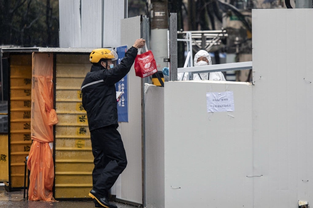 A worker receives a delivery from a courier at a locked down neighbourhood in Shanghai on Friday. Photo: Bloomberg