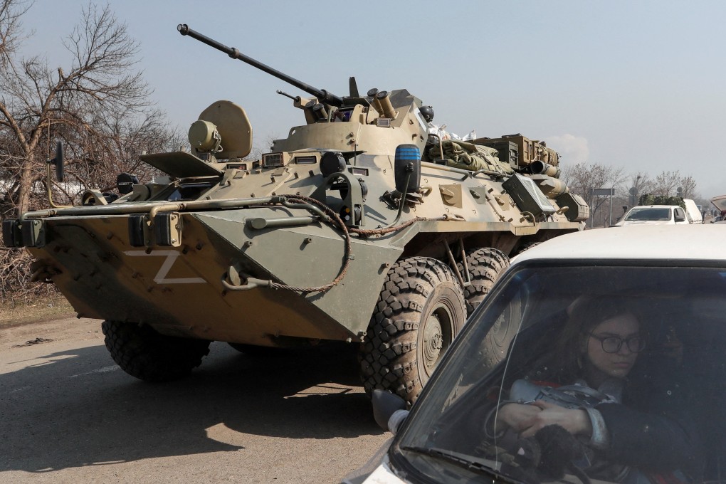 A refugee waits in a car as an APC carrying pro-Russian troops drives out of a checkpoint in the besieged port city of Mariupol, Ukraine on Thursday. Photo: Reuters