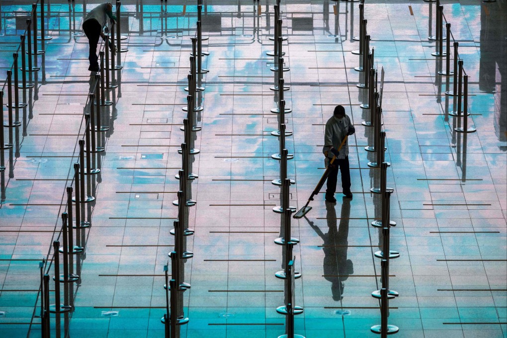 Workers clean an area for arriving passengers at Hong Kong International Airport on March 21. Photo: AFP