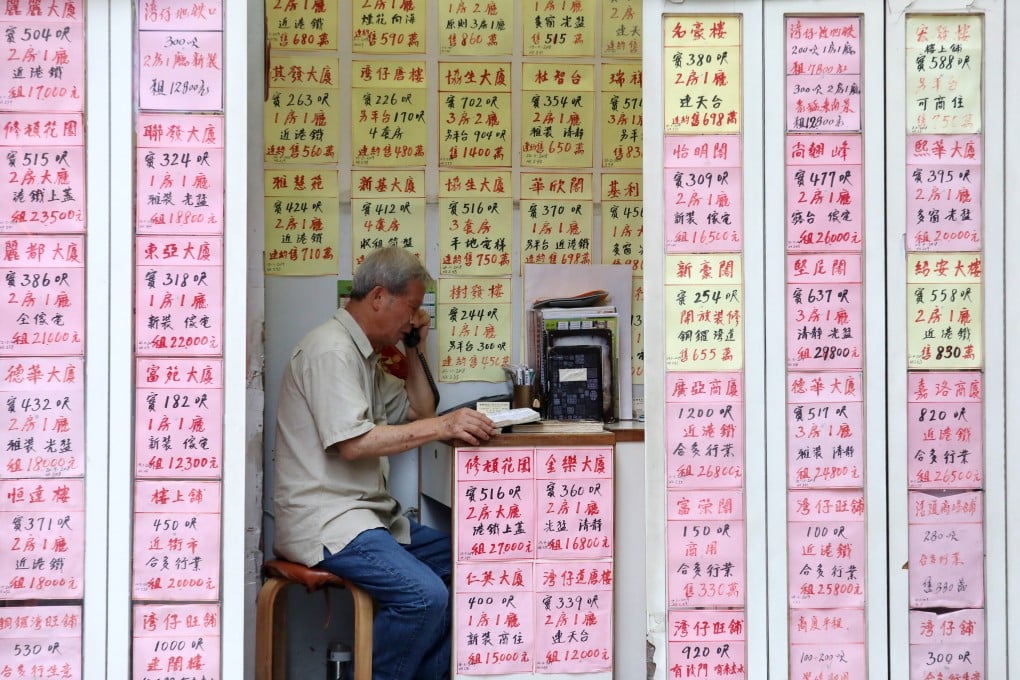 An estate agent talks on the phone inside a real estate agency in Wan Chai. Photo: Felix Wong